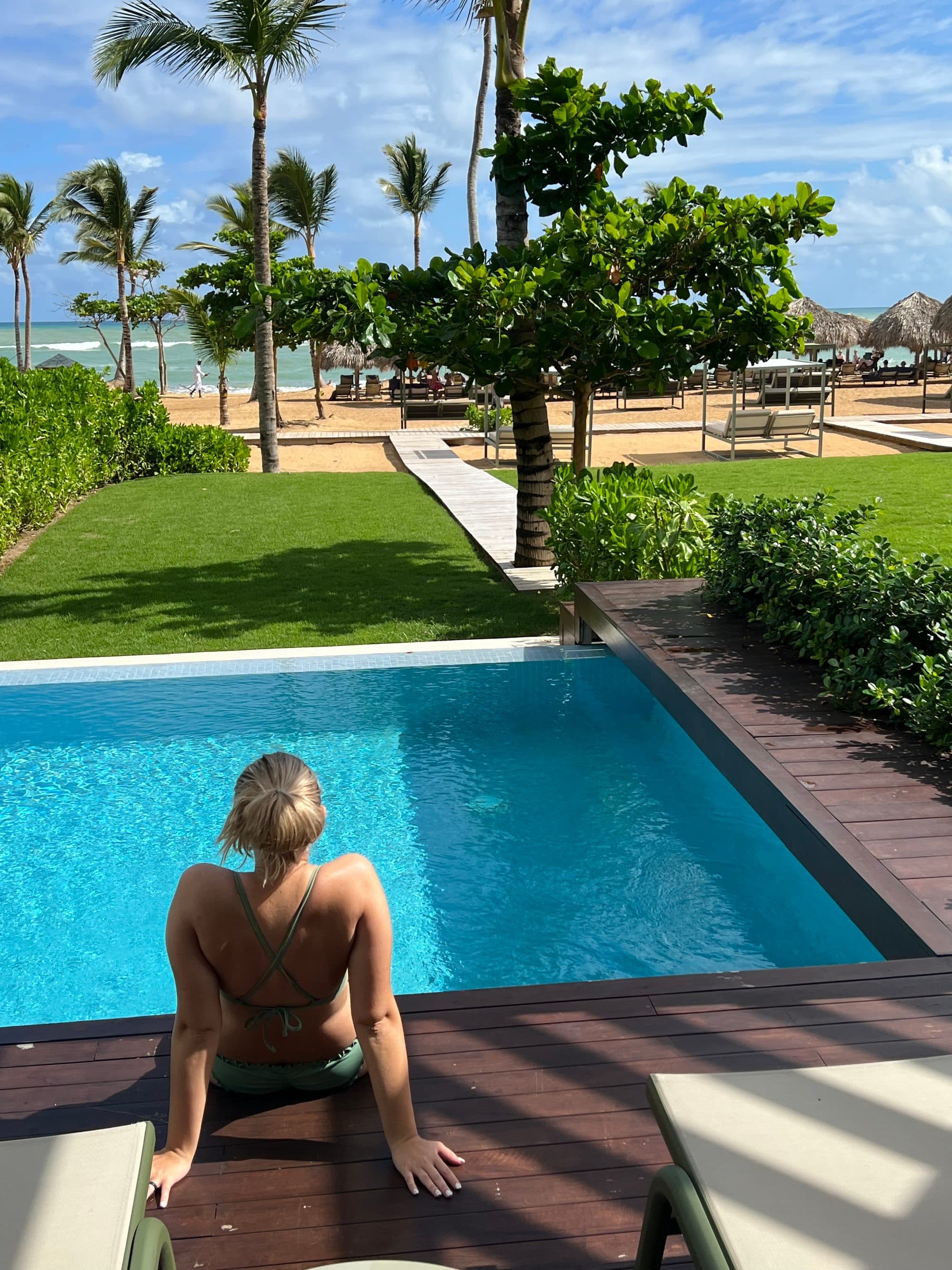 Guest relaxing at the edge of an infinity pool overlooking the beach